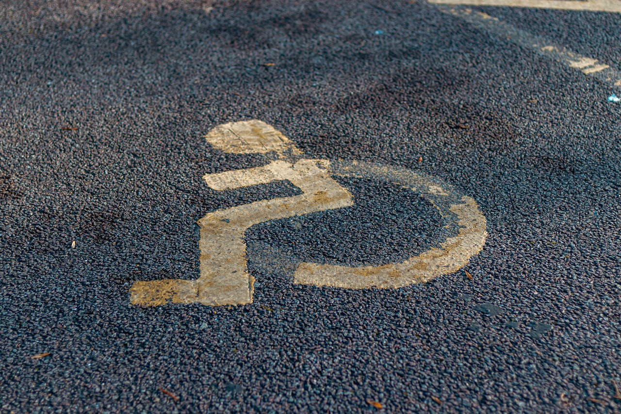 hero-img-01 Close-up of a weathered handicap sign painted on a pavement, emphasizing accessibility.