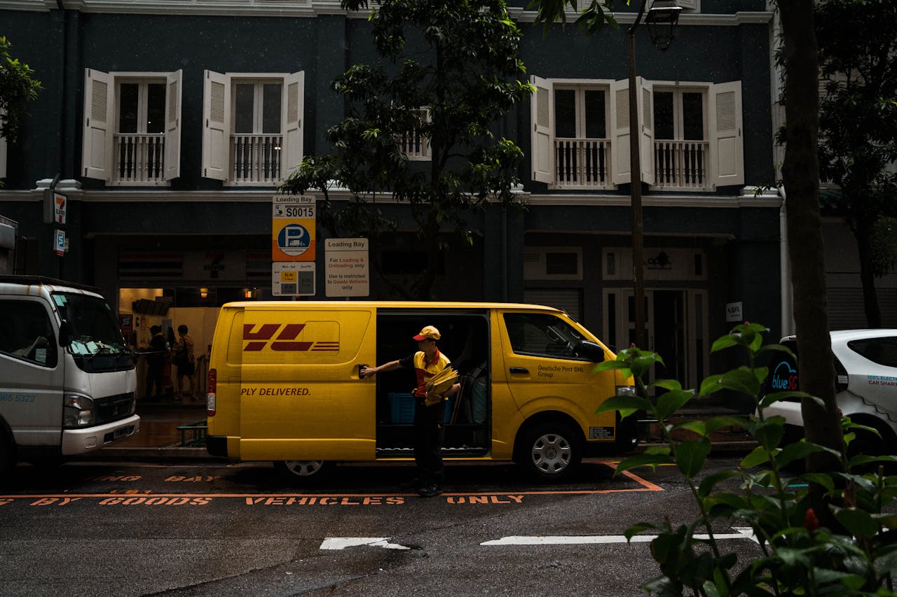 our-services-3 A delivery worker unloading a yellow van in a vibrant Singapore street scene.